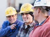 Three smiling construction workers discussing how to maximize their business