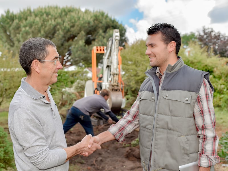 Landscaping business owner smiling and shaking hands with a new customer